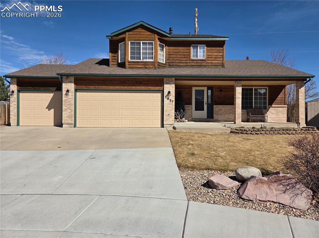 Image 34 of 38: View of front facade with concrete driveway, covered porch, a garage, brick