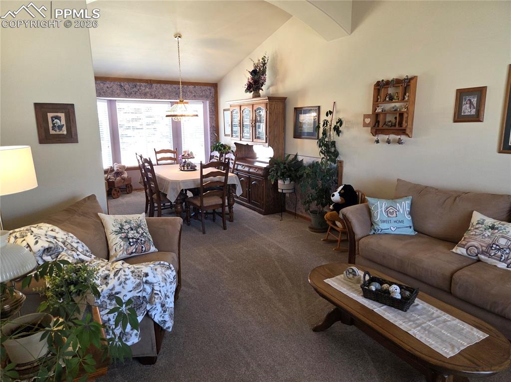 Image 6 of 38: Carpeted living area featuring vaulted ceiling