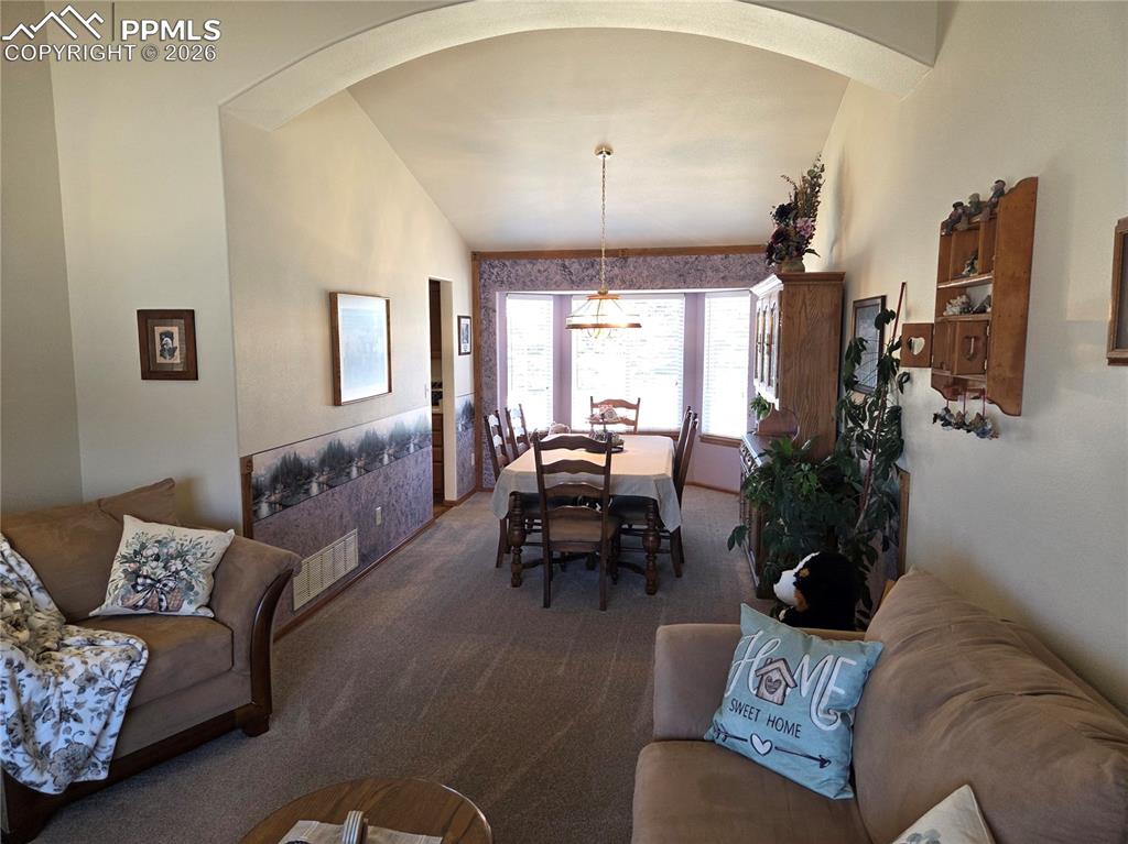Image 7 of 38: Dining area featuring vaulted ceiling, carpet floors, and arched walkways
