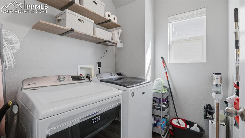 Image 20 of 50: Main Level Laundry Room with built-in shelving and washer and dryer that st