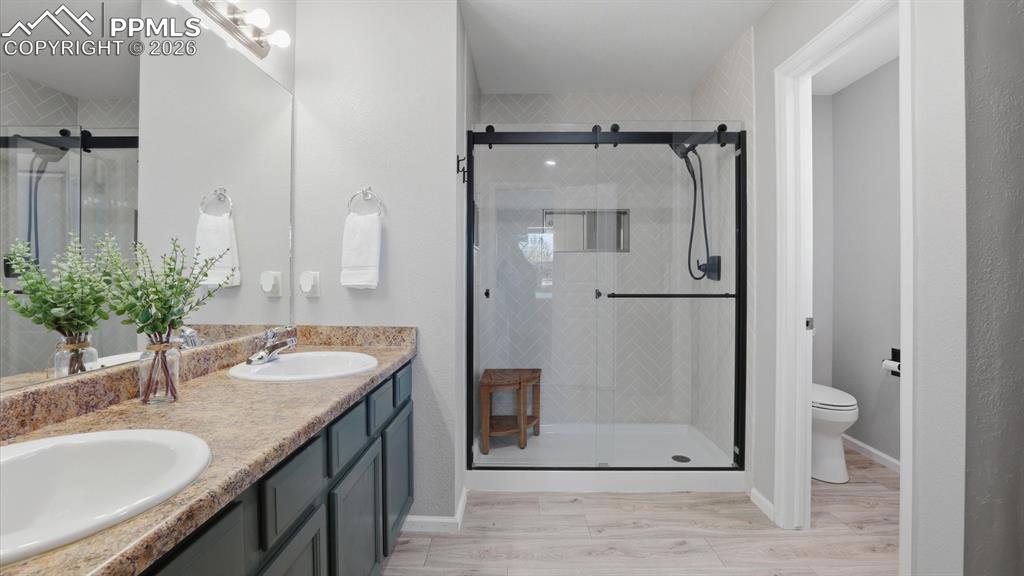Image 26 of 50: Ensuite Primary Bathroom with dual sink vanities, mirror, and enclosed tile