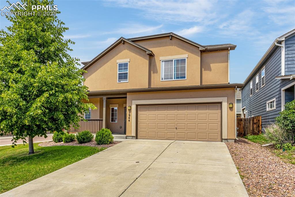 Caption: Traditional-style home featuring an attached garage, driveway, stucco siding, and covered porch