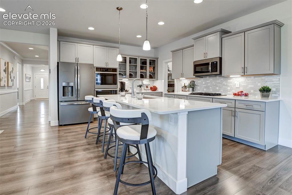 Image 11 of 31: Kitchen with wood-finish flooring, white quartz countertops, stainless stee