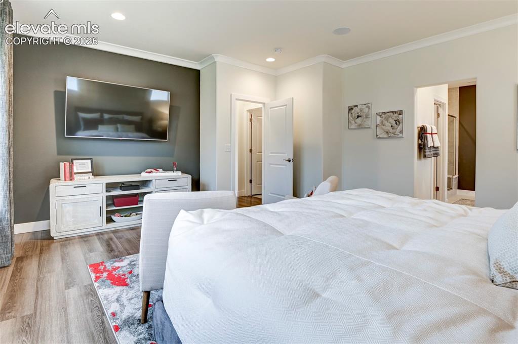 Image 16 of 31: Recessed lighting, crown molding, wood-finish flooring, and a wall-mounted