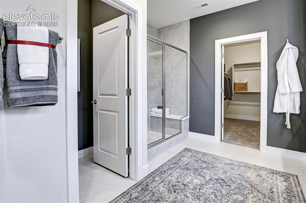 Image 18 of 31: Walk-in shower with clear glass enclosure and integrated bench