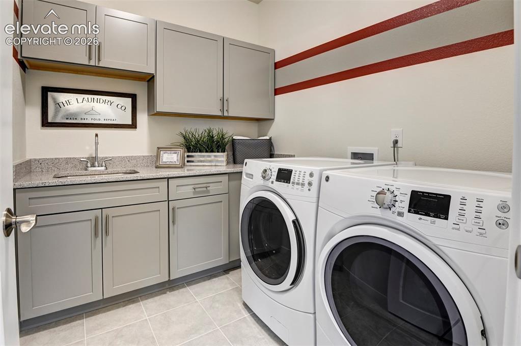 Image 24 of 31: Laundry area with light gray cabinetry, granite-finish countertop, and a bu