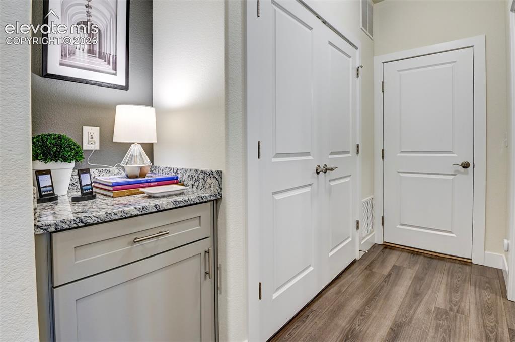Image 4 of 31: Built-in cabinetry with a granite countertop, wood-finish flooring, and whi