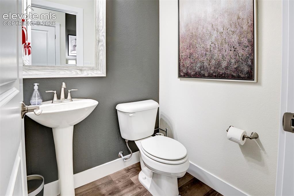 Image 5 of 31: Pedestal sink with a polished chrome faucet, white toilet, and wood-finish 