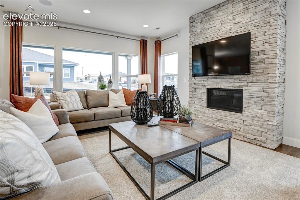 Image 6 of 31: Expansive wall of windows, recessed ceiling lighting, stone-clad fireplace 