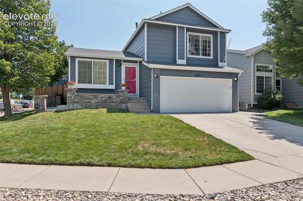 Caption: Two-story residence with a gray siding exterior, an attached two-car garage, concrete driveway, and 