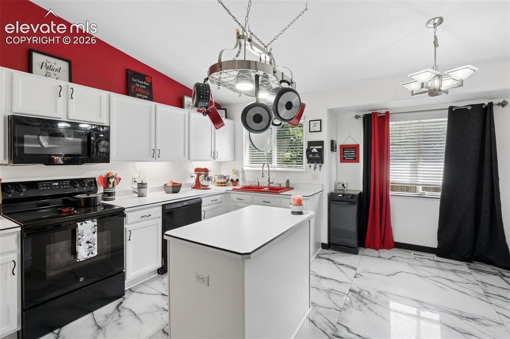 Image 2 of 31: White cabinetry with dark hardware, black appliances, a central island, and