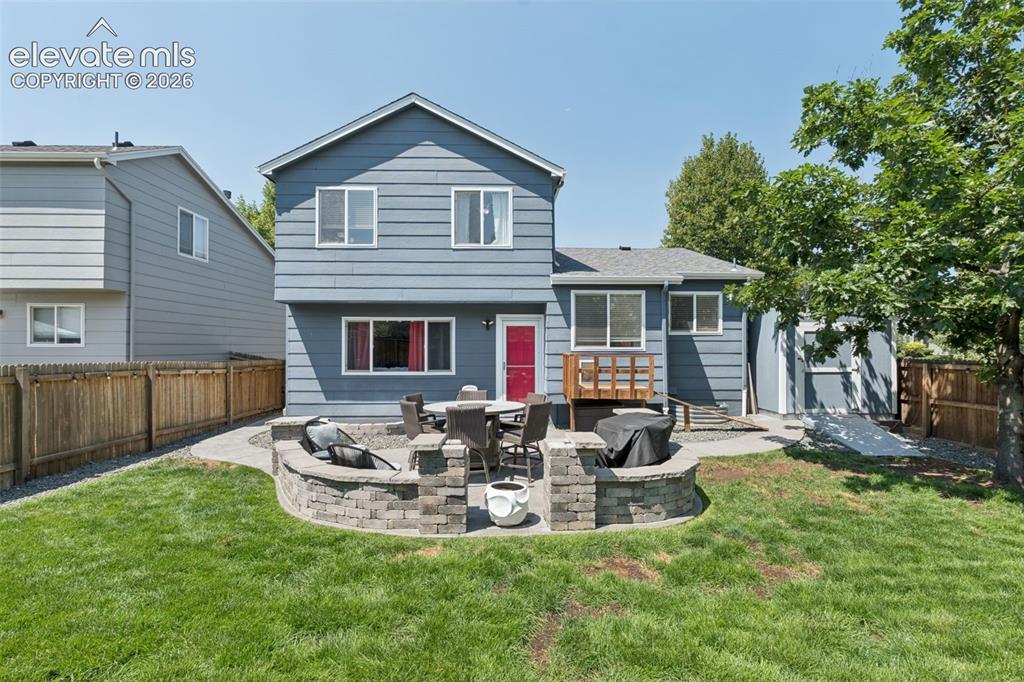 Image 21 of 31: Expansive backyard with a manicured lawn, a stone-built patio, and a dedica