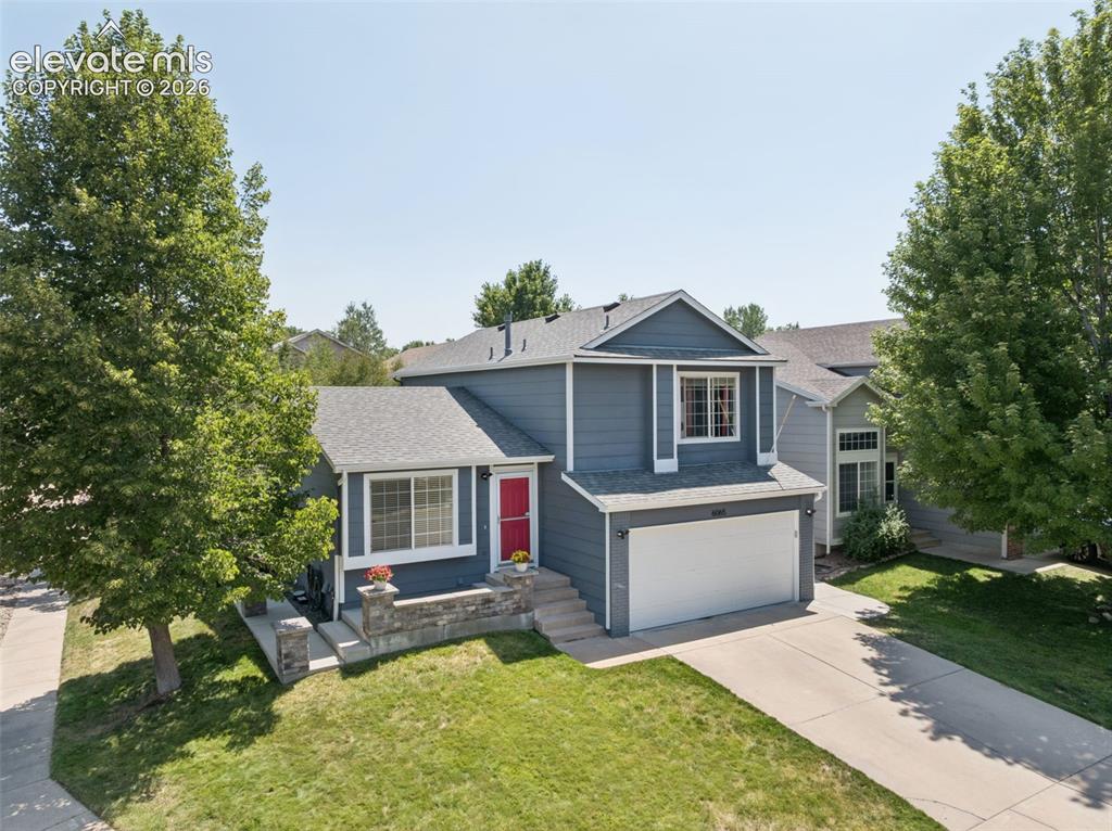 Image 24 of 31: Two-story residence featuring a gray exterior, attached garage, and a red e