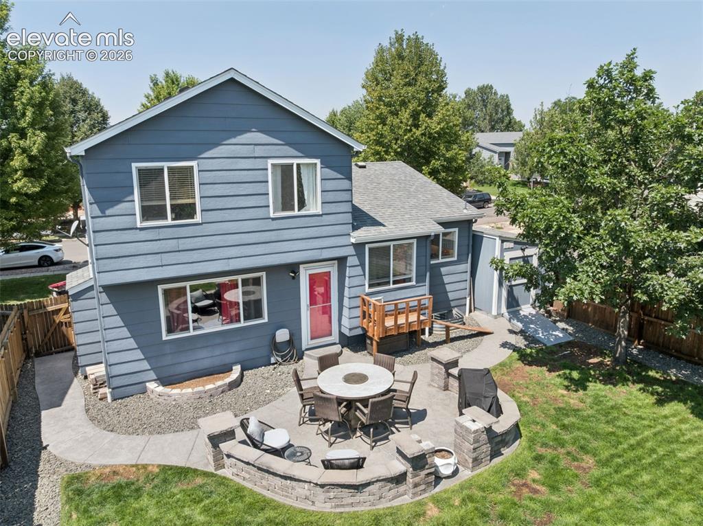 Image 29 of 31: Two-story residence with blue siding, a multi-level patio with stone retain
