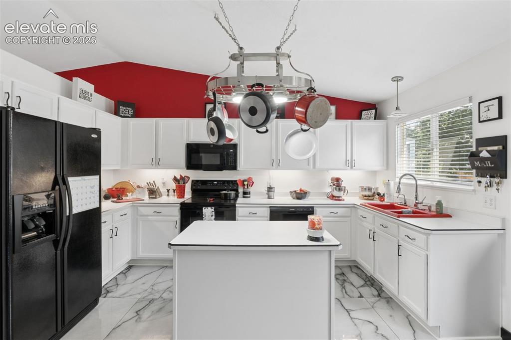 Image 3 of 31: Kitchen featuring white cabinetry, a central island, a pot rack, black appl