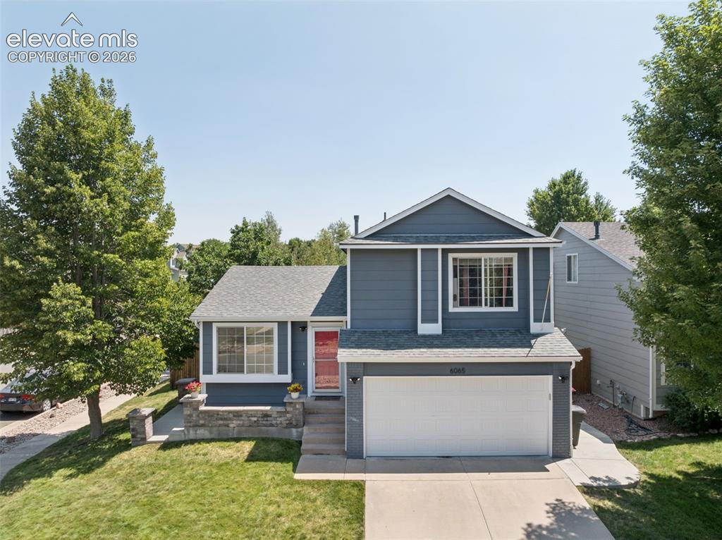 Image 30 of 31: Two-story home with a two-car garage, gray siding, and a red entry door