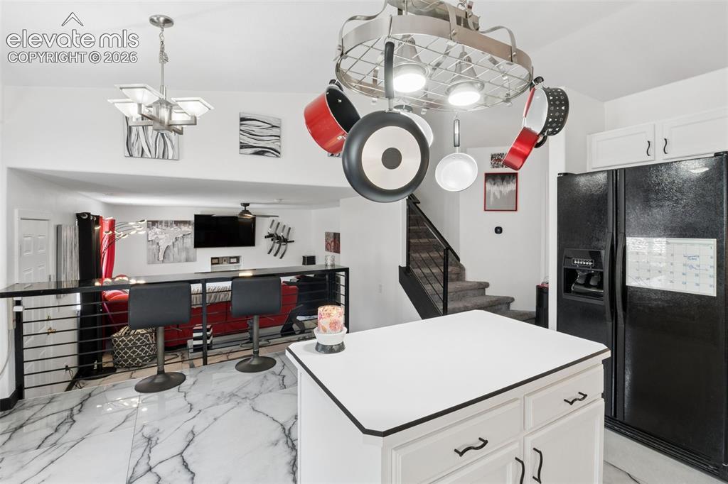 Image 4 of 31: Kitchen featuring an island, white cabinetry, and a black refrigerator