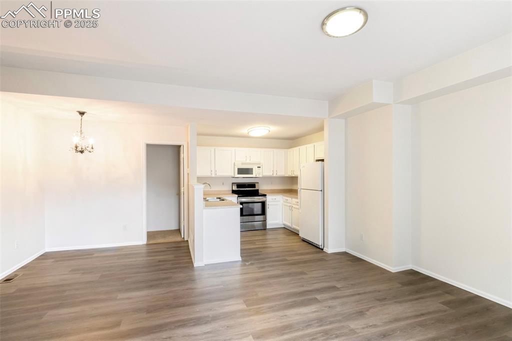 Image 10 of 31: Kitchen with open floor plan, light countertops, white cabinetry, white app