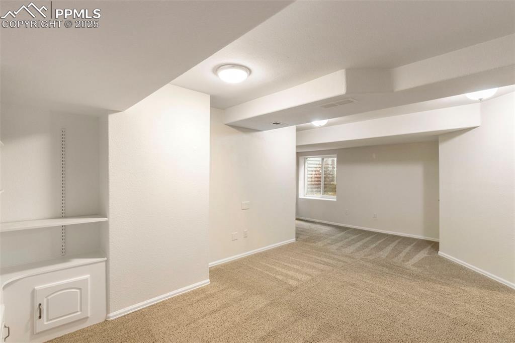 Image 23 of 31: Basement with light colored carpet and baseboards
