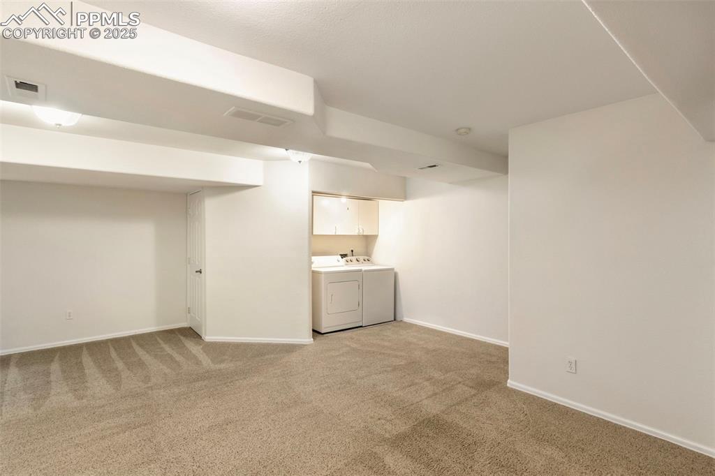 Image 24 of 31: Finished below grade area featuring light colored carpet and washing machin