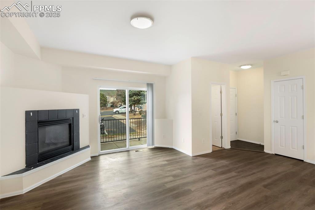 Image 4 of 31: Unfurnished living room with a tile fireplace and dark wood-style floors