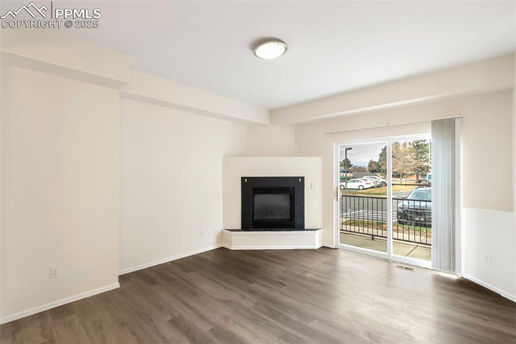 Image 5 of 31: Unfurnished living room with a tiled fireplace and wood finished floors