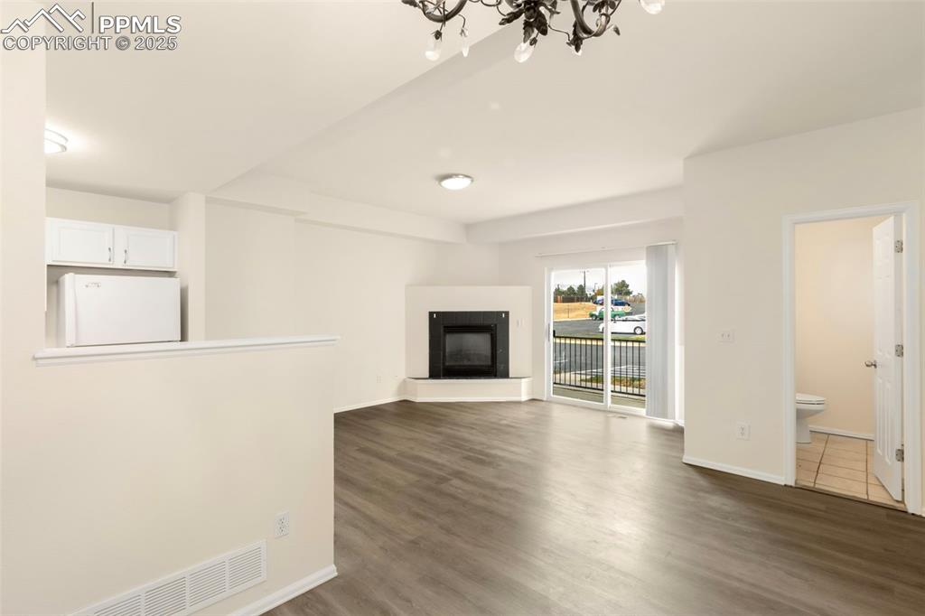 Image 7 of 31: Unfurnished living room with a glass covered fireplace, dark wood finished