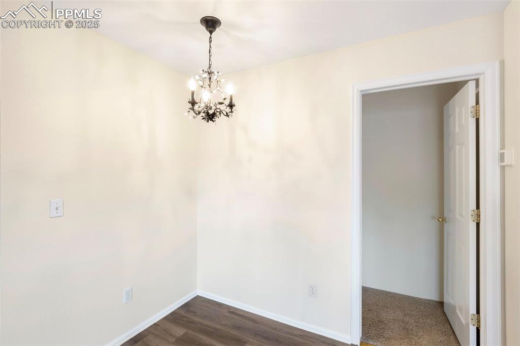 Image 9 of 31: Unfurnished dining area with a chandelier and dark wood-style floors