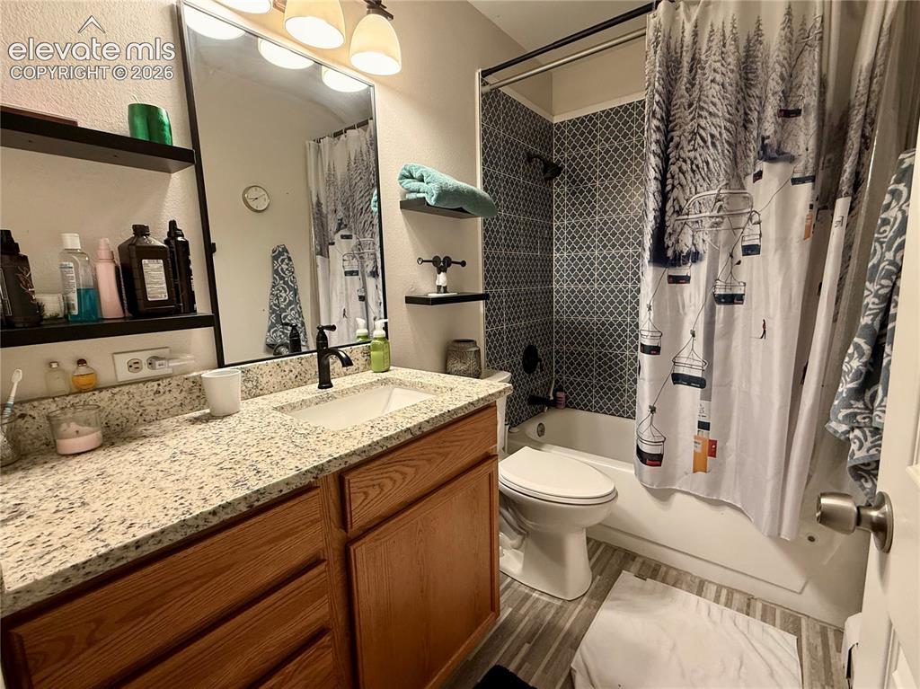 Image 20 of 35: Bathroom featuring a wood-finish vanity with a granite-look countertop, an