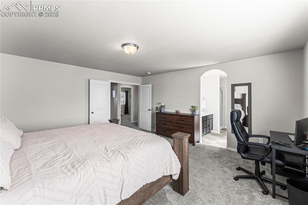 Image 11 of 40: Bedroom with carpet flooring, arched walkways, an office area, and ensuite 