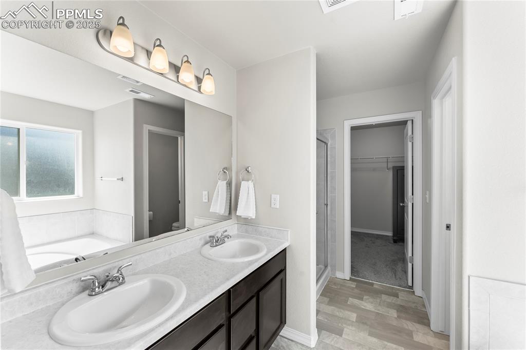 Image 12 of 40: Full bathroom featuring light wood finished floors, a shower stall, double 