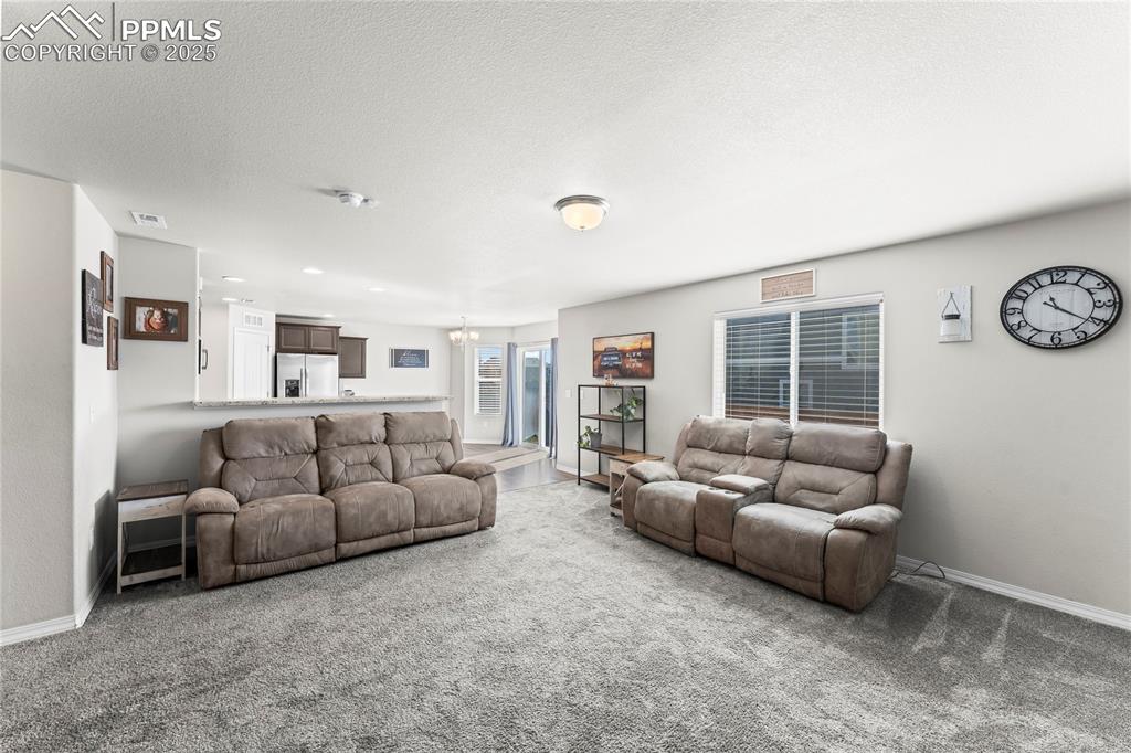 Image 17 of 40: Living room with carpet flooring, a textured ceiling, and a chandelier