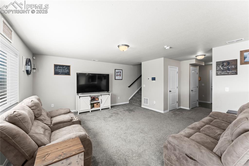 Image 19 of 40: Carpeted living area featuring baseboards and stairs