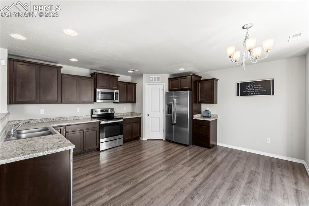 Image 20 of 40: Kitchen featuring dark brown cabinetry, appliances with stainless steel fin