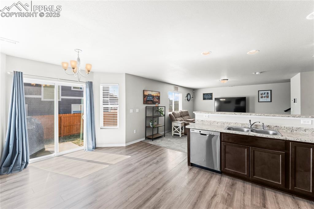 Image 23 of 40: Kitchen featuring dishwasher, a chandelier, dark brown cabinetry, open floo
