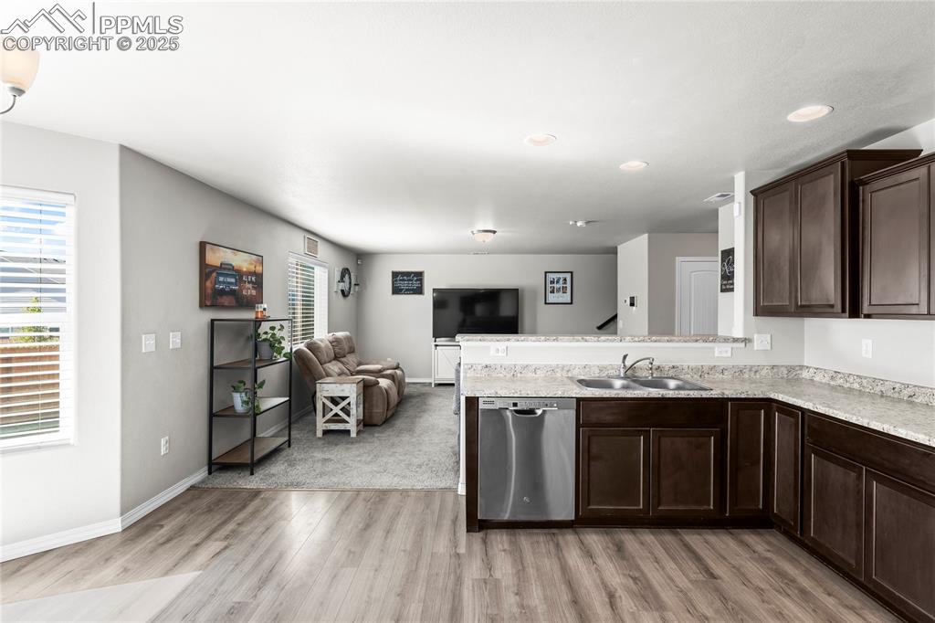 Image 24 of 40: Kitchen with a peninsula, dark brown cabinets, dishwasher, open floor plan,