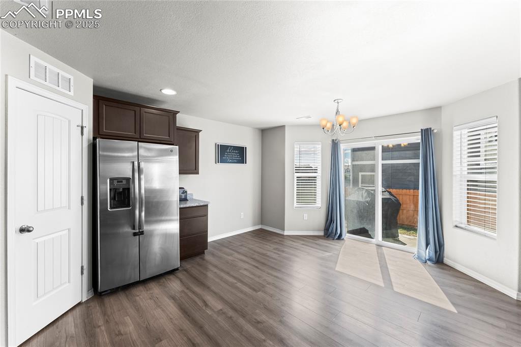 Image 25 of 40: Kitchen featuring dark brown cabinets, stainless steel fridge, a chandelier