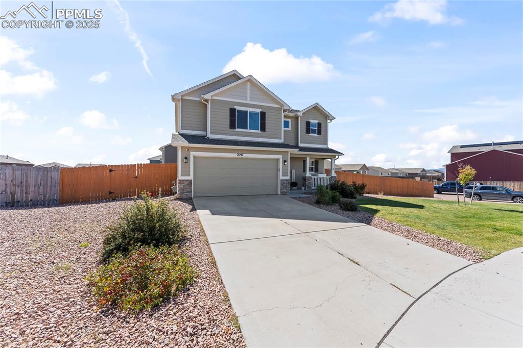 Image 3 of 40: View of front of home with driveway, an attached garage, stone siding, and 