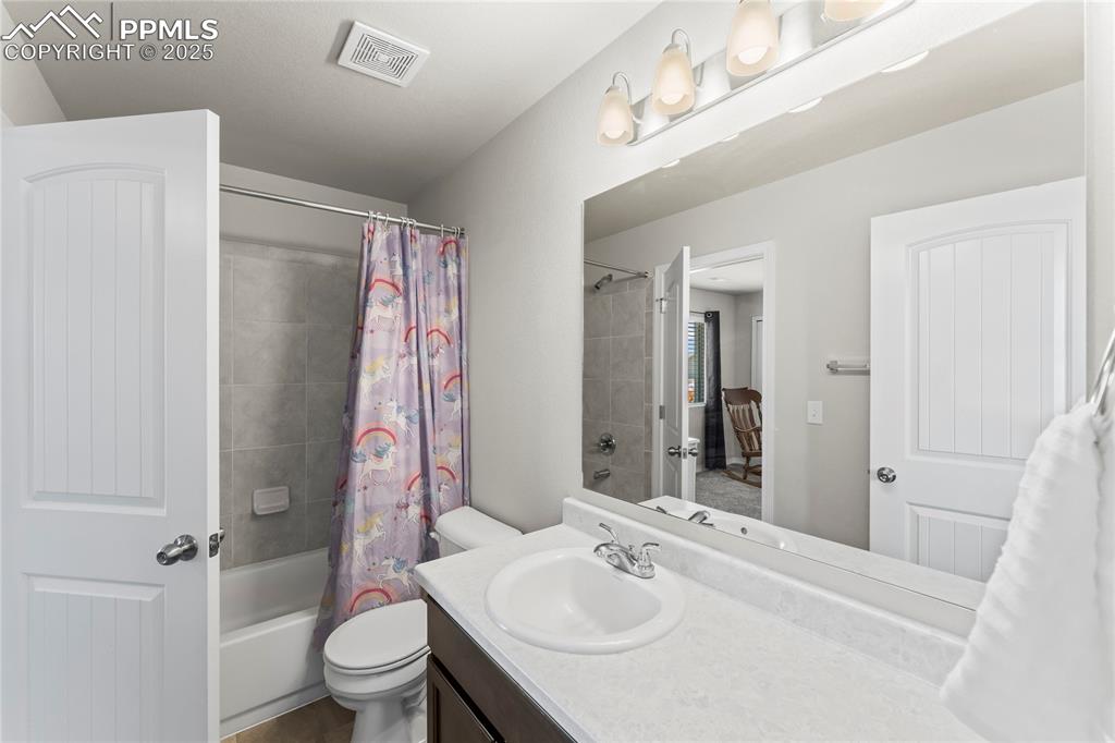Image 33 of 40: Bathroom with shower / tub combo with curtain and vanity