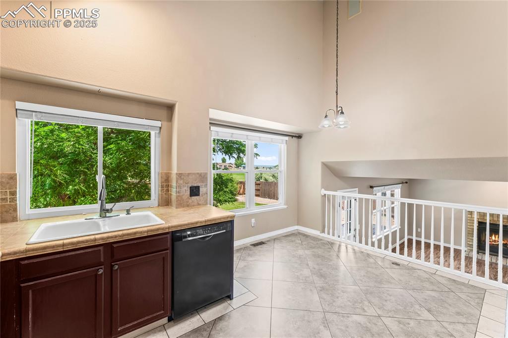 Image 11 of 42: Kitchen featuring black dishwasher, a warm lit fireplace, a high ceiling, l