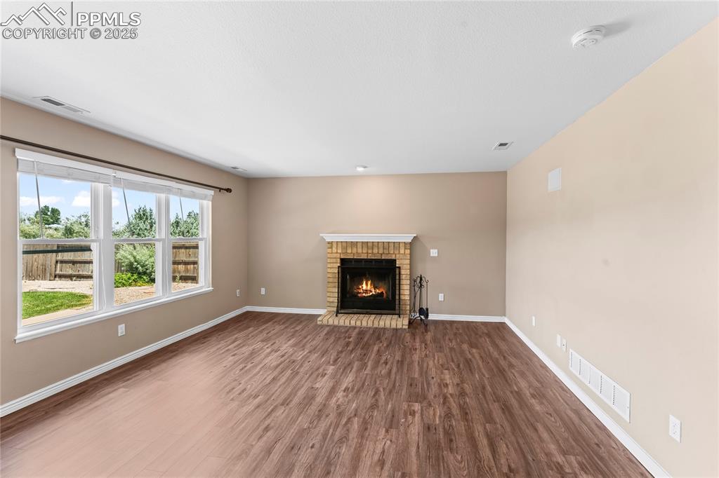 Image 14 of 42: Unfurnished living room with dark wood-style flooring and a fireplace