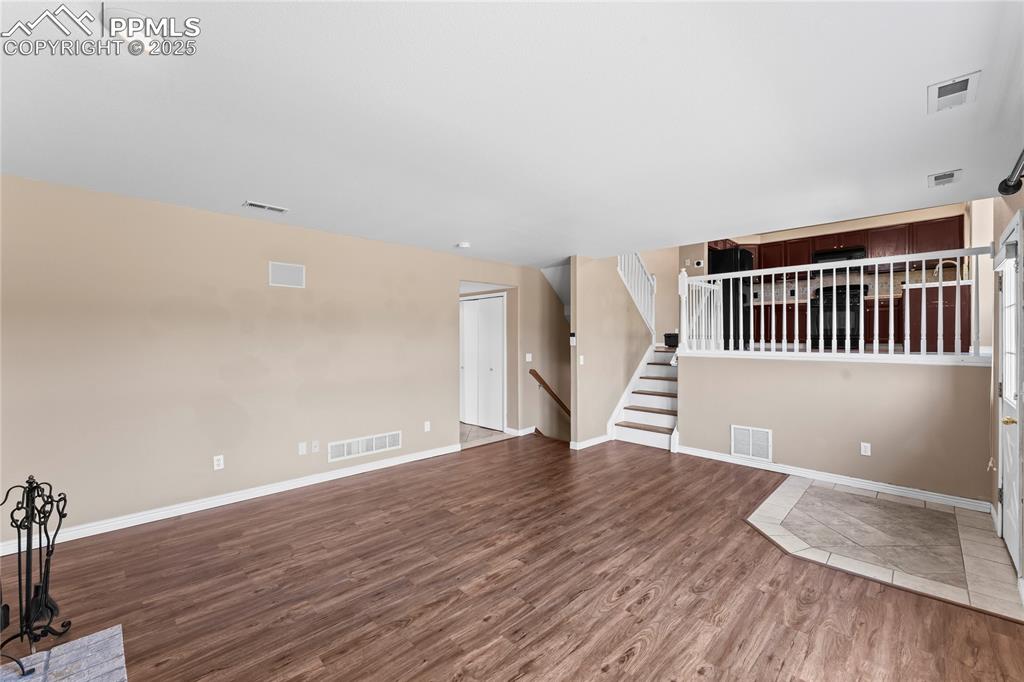 Image 15 of 42: Unfurnished living room with wood finished floors and stairs