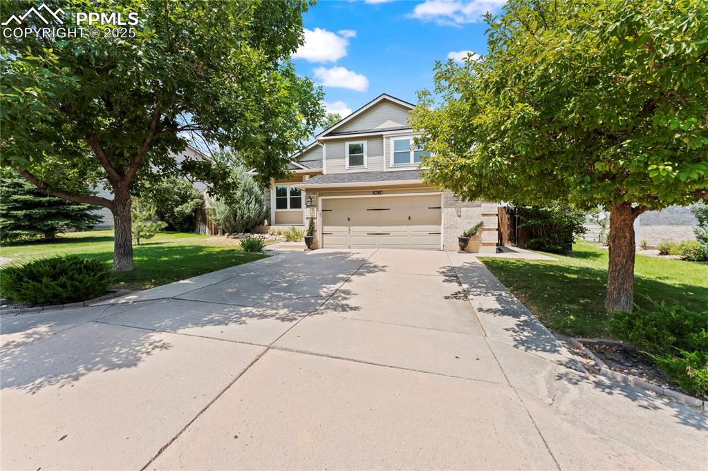 Image 2 of 42: Obstructed view of property with driveway, a front yard, a garage, and bric