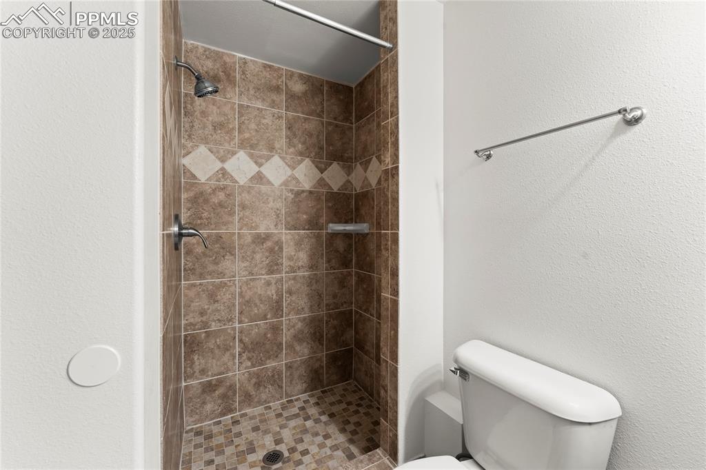 Image 24 of 42: Full bath featuring a shower stall and a textured wall