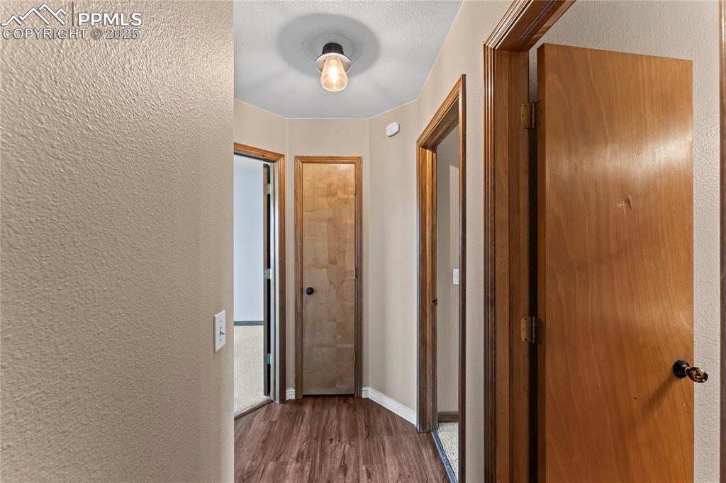 Image 27 of 42: Hallway with a textured wall, wood finished floors, and a textured ceiling