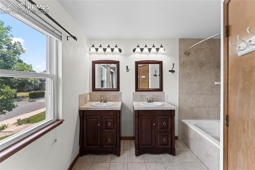 Image 37 of 42: Bathroom featuring vanity, tiled shower / bath combo, and tile patterned fl