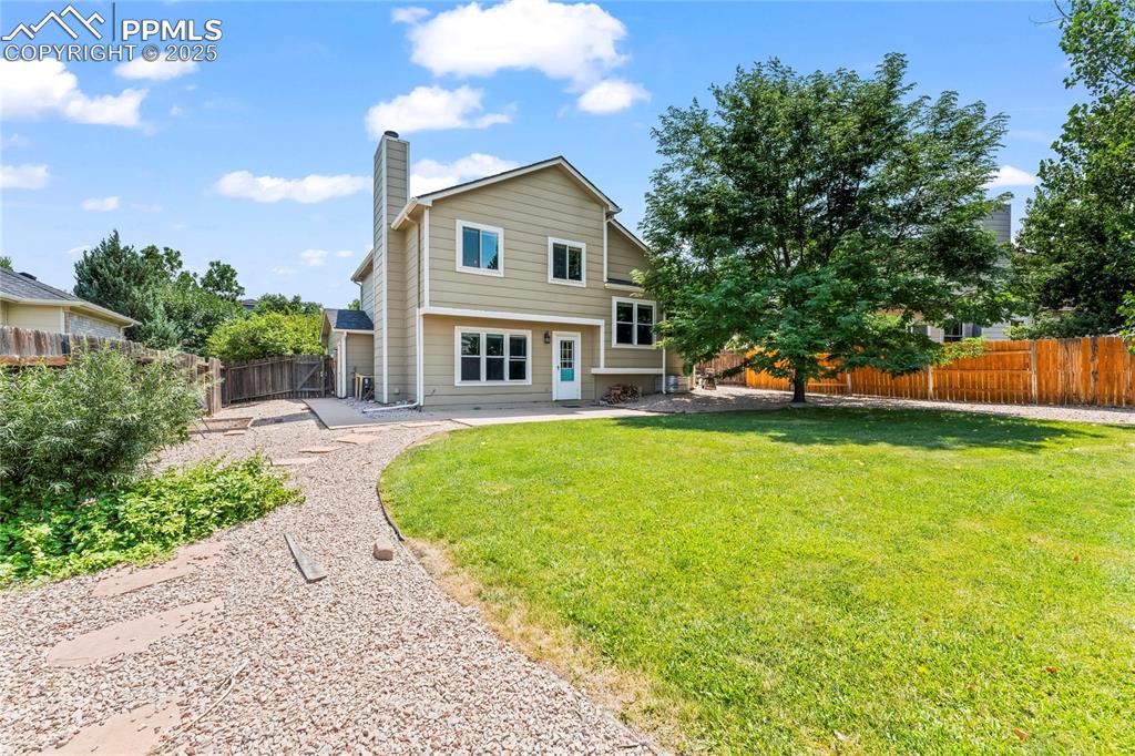 Image 40 of 42: Rear view of house with a fenced backyard, a chimney, and a patio