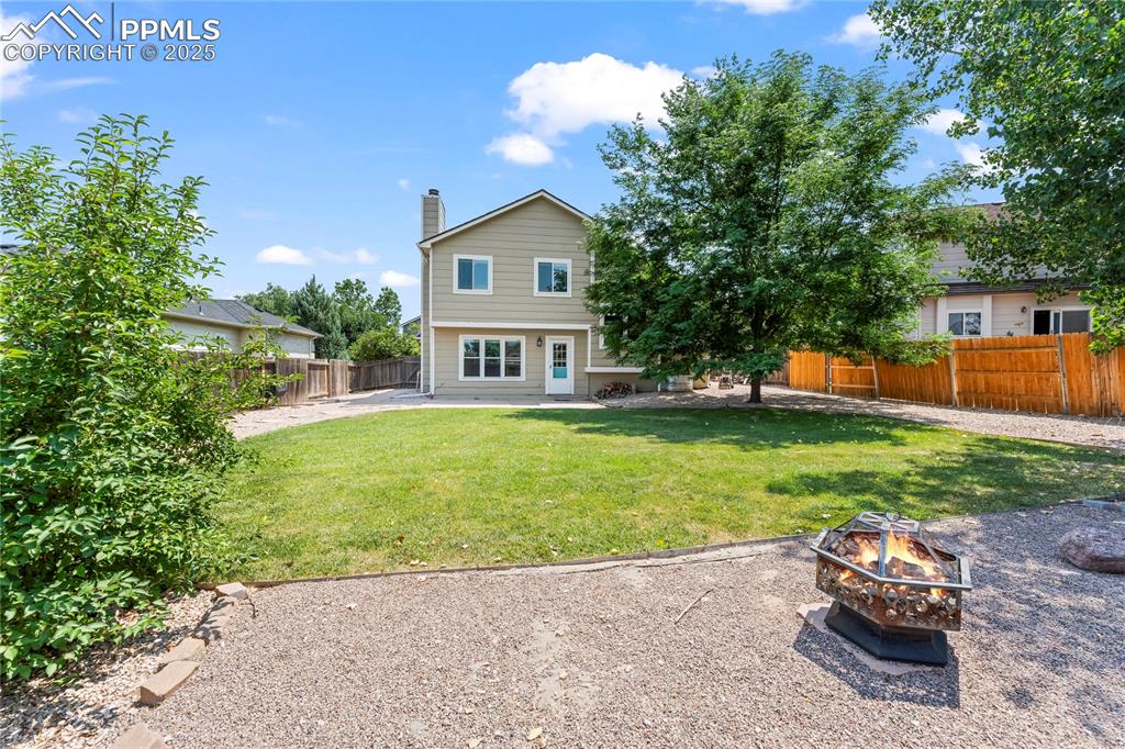 Image 41 of 42: Back of property with a fire pit, a chimney, a fenced backyard, and a patio