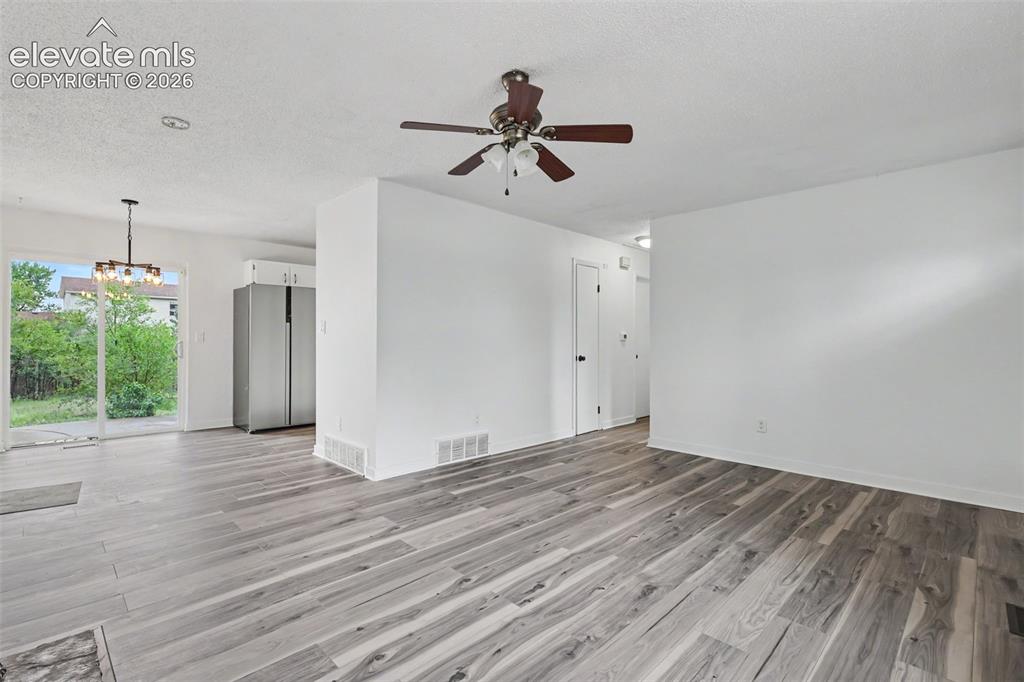 Image 16 of 43: Spacious living area featuring wood-finish flooring, white walls, and a cei