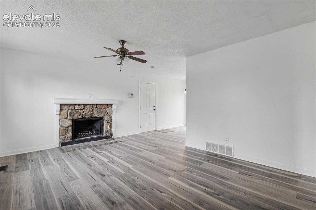 Image 18 of 43: Living area featuring a stone fireplace with a white mantel, wood-finish fl